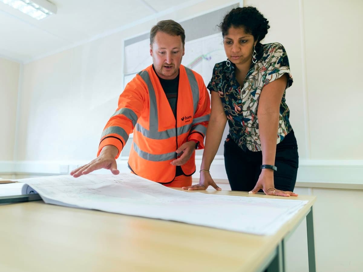 Sales engineer in a hi-vis vest and a customer going through a technical drawing