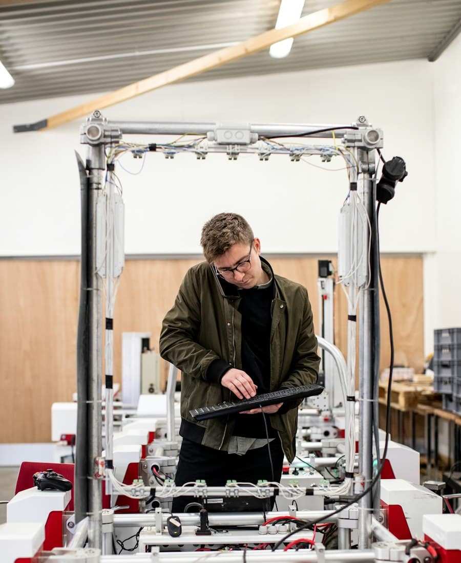Technician with a keyboard at a machine frame in a workshop