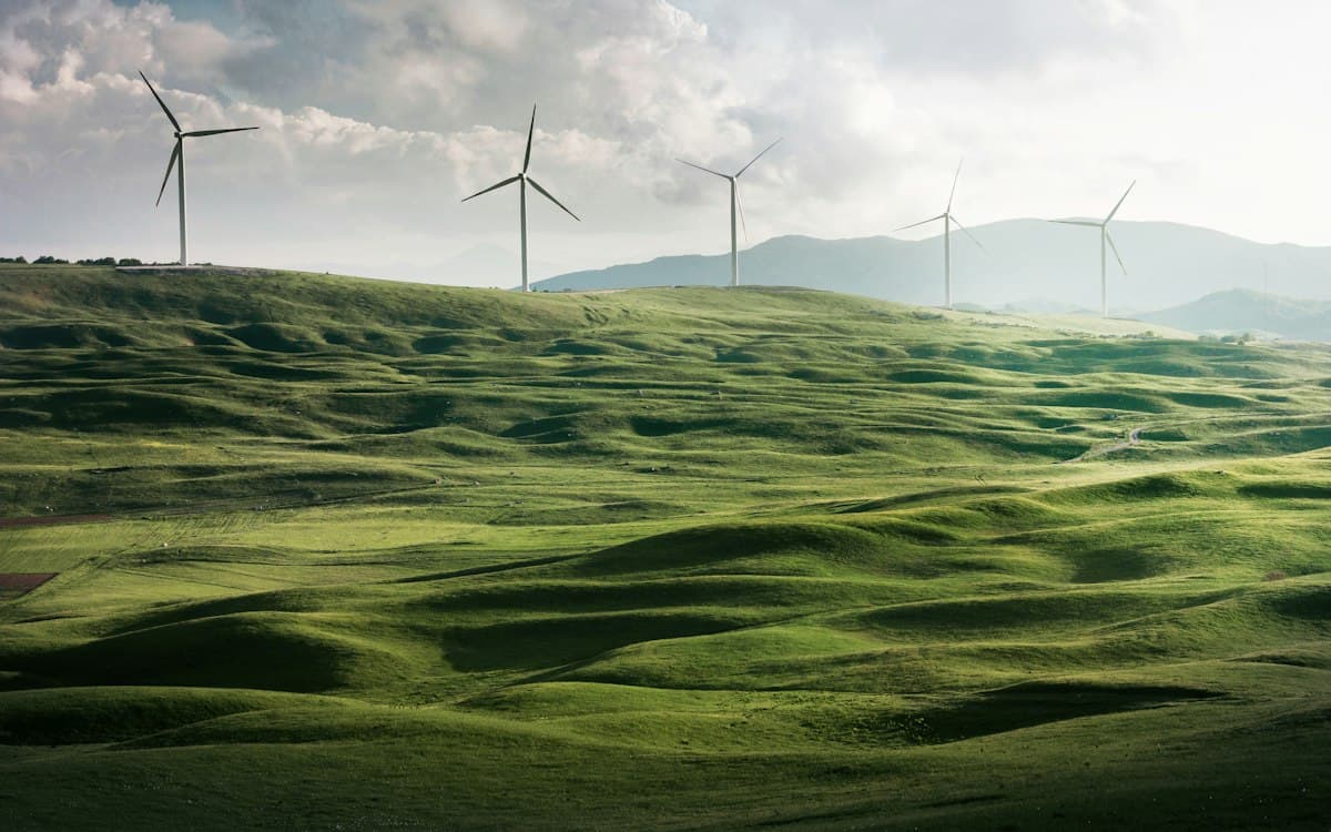 Wind turbines on green hills under a cloudy sky