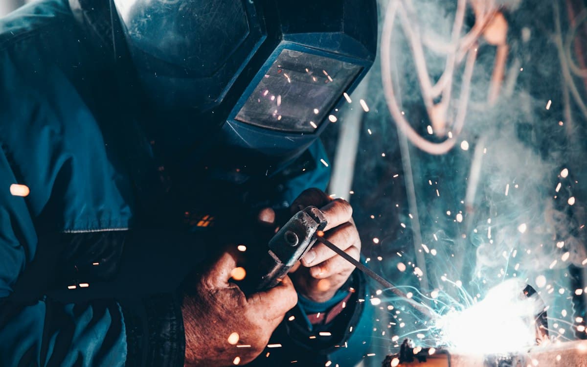 Welder in a protective mask, sparks flying from the weld seam
