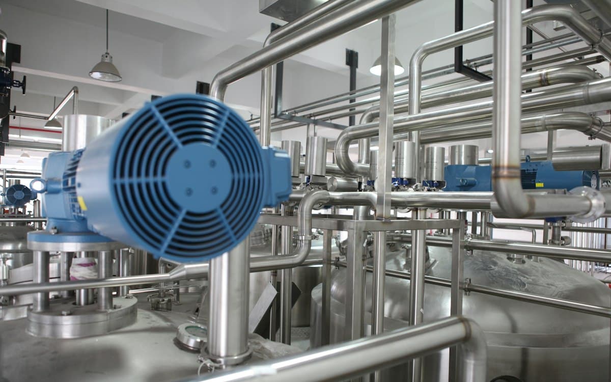 Stainless-steel process plant with pipework and pumps in a machinery factory