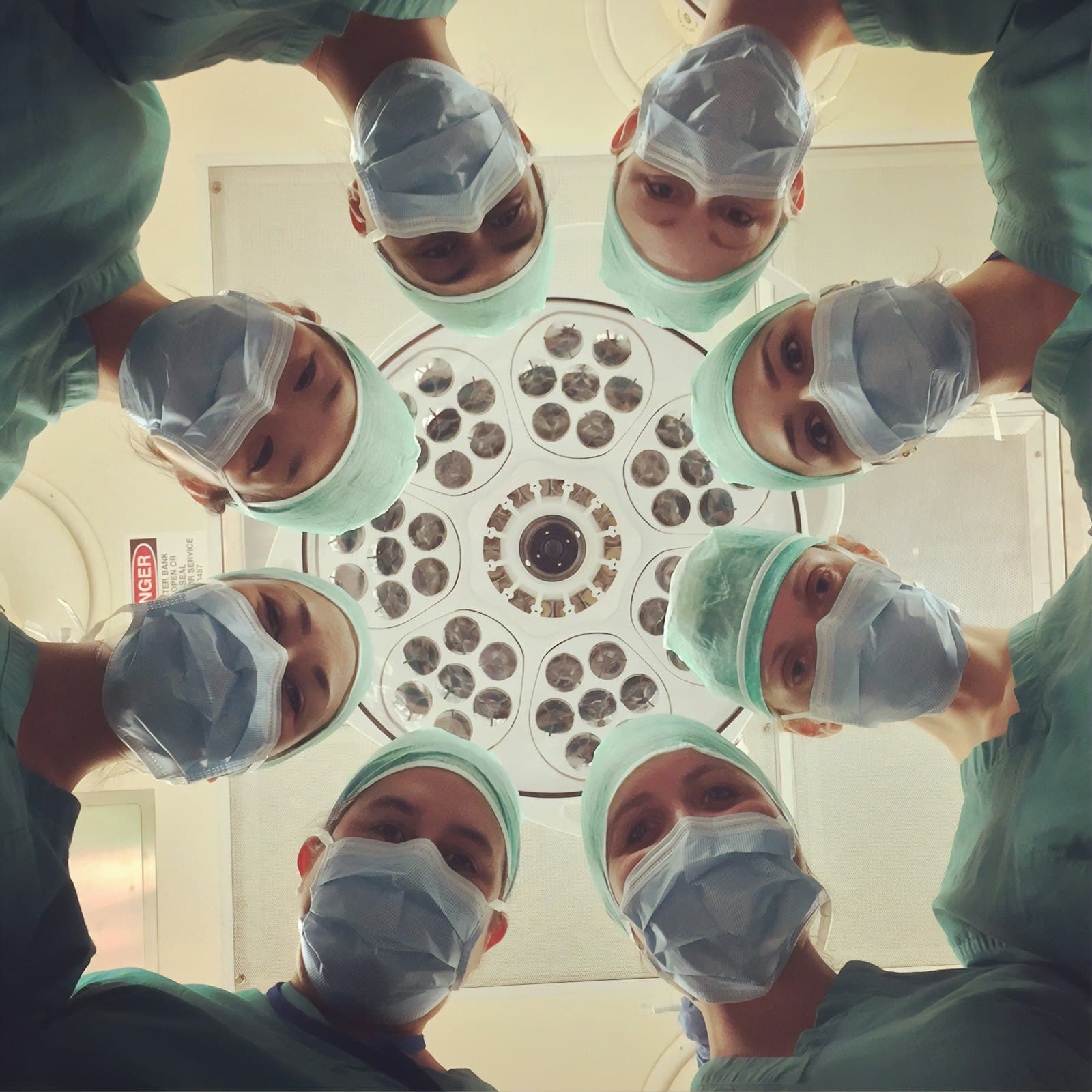 Surgical team in scrubs under the operating light, seen from below