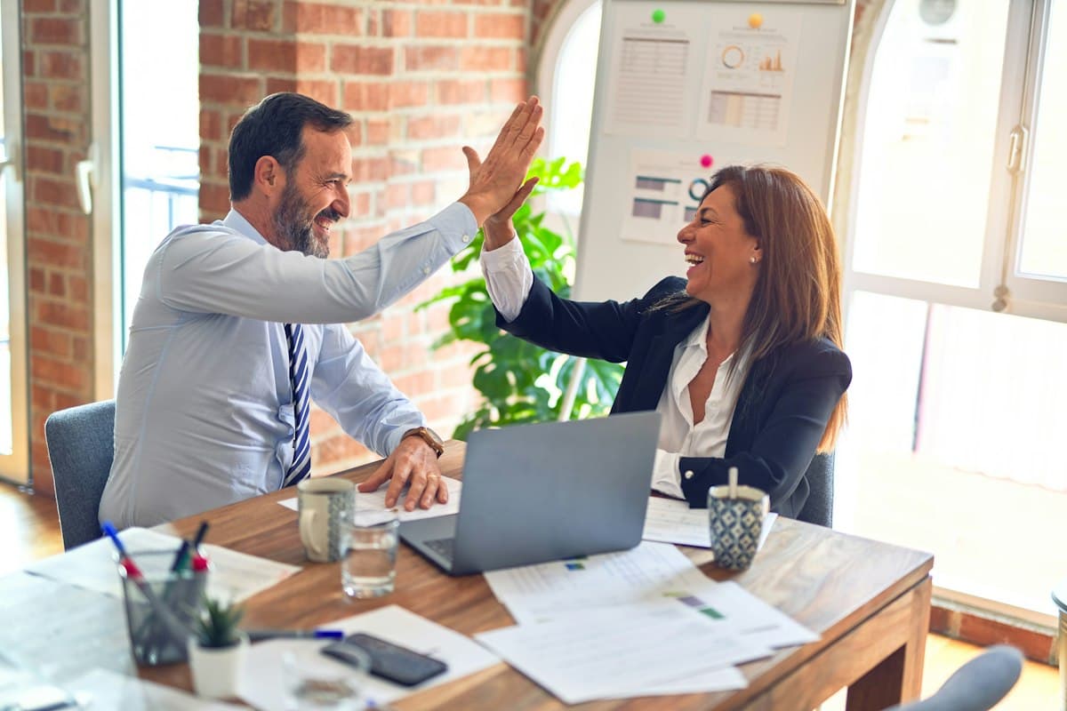 Two colleagues celebrating a closed deal at their desk