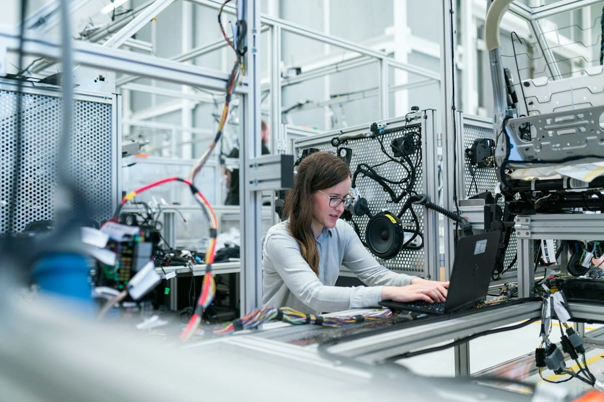 Engineer with a laptop at a test rig in a production hall – Technical Sales Jobs